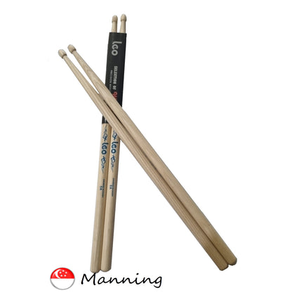 Three wooden drumsticks with a black label on a white background, featuring the Manning brand logo.